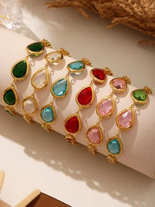 Detail of gold ankle bracelets featuring colorful pear-cut glass stones on a display