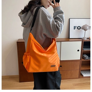 Frau mit großer orangefarbener Segeltuch-Umhängetasche zeigt das geräumige Design