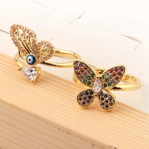 Close-up of gold butterfly rings with colorful cubic zirconia on a wooden stand