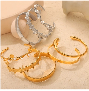 Detail view of 18k gold and silver plated titanium steel bracelets with pearls and carvings