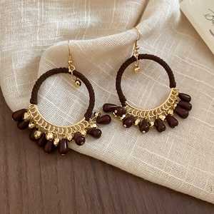 Close-up of Bohemian gold hoop earrings with brown fabric wrap and water-drop beads