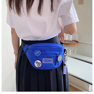 Close-up of bright blue canvas sling bag with fashion badges and astronaut pendant