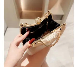 Detail of champagne pleated evening clutch with pearl clasp and golden chain strap