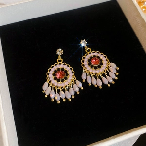 Close-up of vintage flower tassel earrings with red crystals on a black velvet display