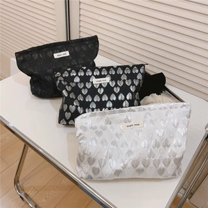 Three canvas heart jacquard makeup bags with silver and black heart patterns on table