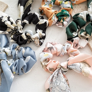 Detailed flat lay of colorful floral satin scrunchies with rabbit ear bow knots