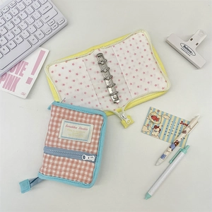 Detail of 3-ring mini binder with pink plaid fabric cover and metal loose-leaf mechanism