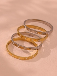 Close-up of gold and silver stainless steel bangles with square pattern and inlaid crystals