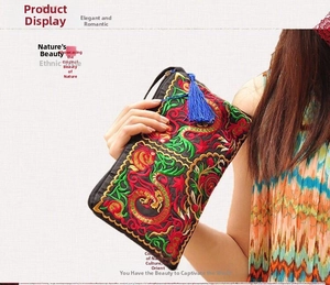Detailed embroidery of ethnic patterns and blue tassel charm on black satin clutch bag