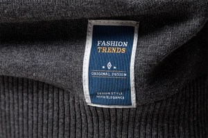 Vue macro détaillée de la texture du tricot gris foncé avec étiquette tissée tendance bleue