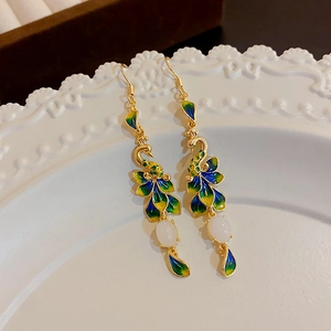 Detail view of peacock crane earrings with gold metal and colorful enamel glaze on a tray