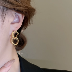 Macro shot of gold double geometric link earrings with metallic luster finish