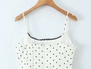 Close-up of black lace trim and polka dot pattern on the white dress bodice