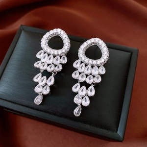 Detailed macro view of silver tassel earrings with round and teardrop zircon stones