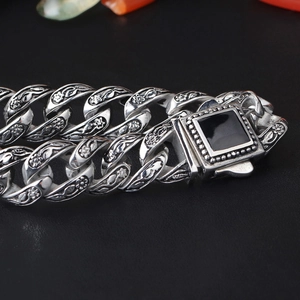 Dettaglio del bracciale vintage in acciaio con rilievo floreale e gemma nera quadrata