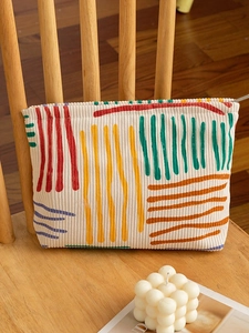 Floral corduroy makeup bag with colorful stripes on a cozy wooden chair setup
