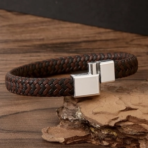 Macro detail of braided leather bracelet with magnetic metal clasp on rustic wood