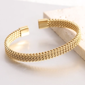 Detail of gold woven mesh bangle featuring polished rectangular ends and metal texture