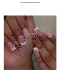 Vue macro de faux ongles français roses avec fleurs dorées 3D et perles décoratives