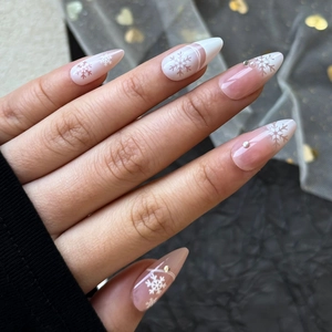 Macro view of almond shaped Christmas nails with white snowflakes and rhinestones