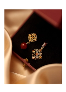 Detail of hollowed flower earrings with cubic zirconia on red velvet and pearl silk