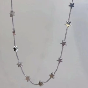 Détail d'un collier chaîne serpent argenté orné de petits pendentifs en étoile
