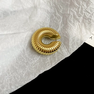 Vue rapprochée d'une boucle d'oreille spirale dorée avec texture vintage polie sur fond blanc