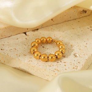 Detailed shot of gold-plated beaded steel ring on light stone tile with cream silk