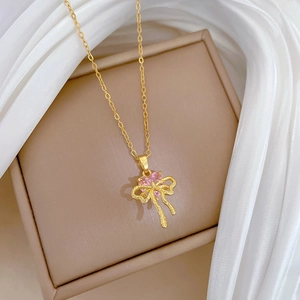 Detail of gold bow necklace with pink heart gemstone on luxury silk and jewelry box