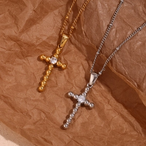 Detail of cross pendants in gold and silver finish with bead texture and central zircon