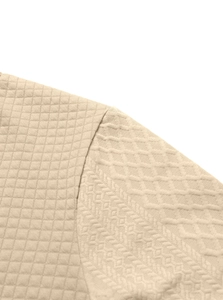 Close-up of beige knitted pullover showing detailed diamond and herringbone stitch patterns