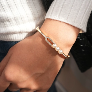 Close-up of luxury gold open cuff bracelet with white pearls and sparkling rhinestones