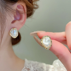 Detail of baroque pearl flower earring with gold-plated frame worn by a model