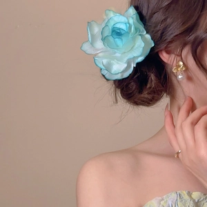 Macro detail of a large gradient white and blue fabric flower hair clip on a model