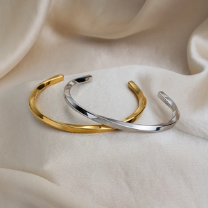 Twisted minimalist open bangles in gold and silver finish on champagne silk fabric