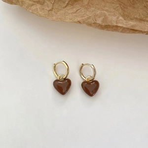 Gros plan détaillé de boucles d'oreilles cœur dorées avec émail marron chocolat