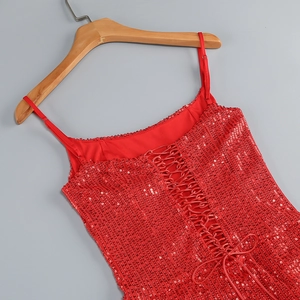 Detail of red sequined dress featuring criss-cross lace-up bodice and sparkling fabric texture