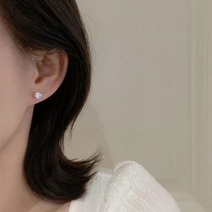 Close-up of minimalist silver stud earring with clear cubic zirconia on a model's ear