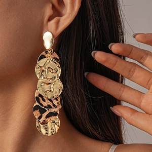 Detail of bohemian long drop earrings with leopard print and hammered gold metal discs
