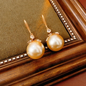 Détail macro de boucles d'oreilles perles dorées avec fleurs en zircon sur bois vintage