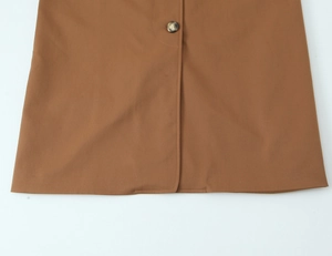 Detailansicht des beigen Trenchcoat-Saums mit Marmorknopf und feiner Textur