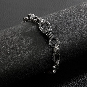 Macro detail of retro stainless steel chain bracelet with a swivel hook on black leather