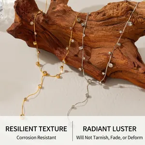 Detail of gold and silver Y-shaped tassel necklaces with inset crystal charms on wood