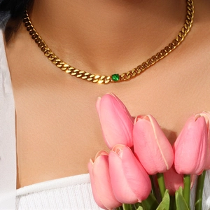 Detail showing 18K gold-plated Cuban link necklace with a round green zircon on a model
