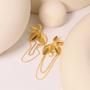 Detailed shot of gold leaf earrings with tassel chains and pearls on minimalist props