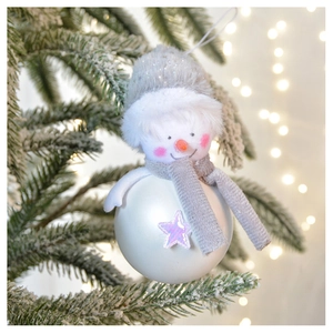 Detailed plush snowman Christmas ornament hanging on a snowy branch with festive warm bokeh