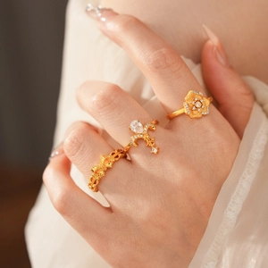 Close-up of three vintage gold rings with zircon flowers and wavy textures on hand