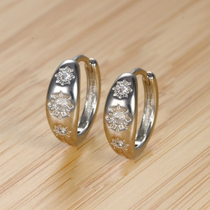 Detailed macro shot of silver hoop earrings with sunburst star pattern and inlaid crystals