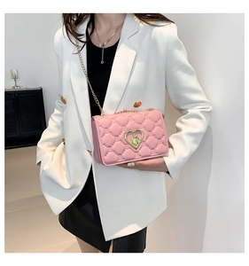 Detail of pink quilted crossbody bag with golden heart-shaped lock and chain strap