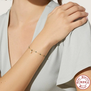 Detail of 925 sterling silver gold bracelet with green beads and pearl on model wrist